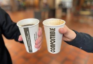 Two people holding compostable beverage cups