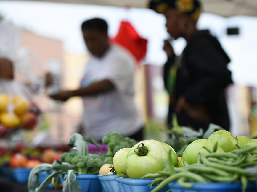 People buying vegetables at farmers market.