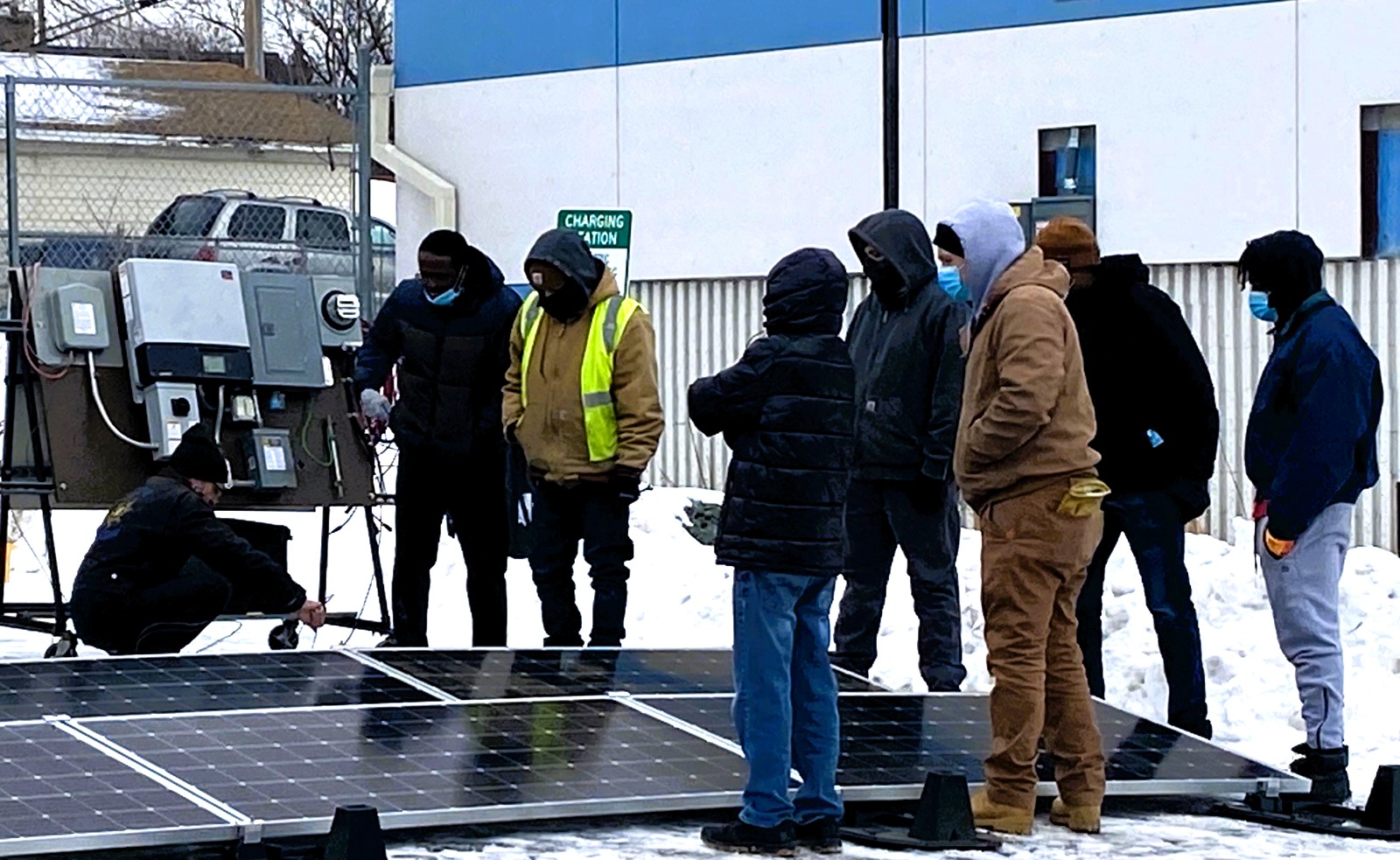 People standing by solar panel.