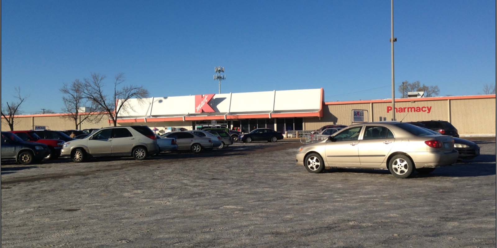 Exterior of former Kmart on Nicollet with large parking lot and cars in foreground