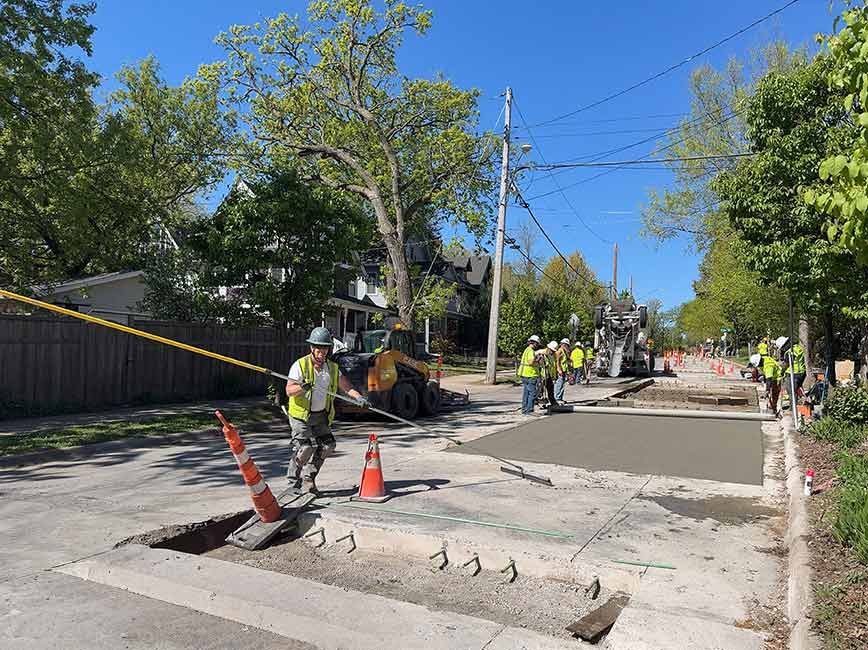 Workers pouring concrete on the road on a sunny summer day