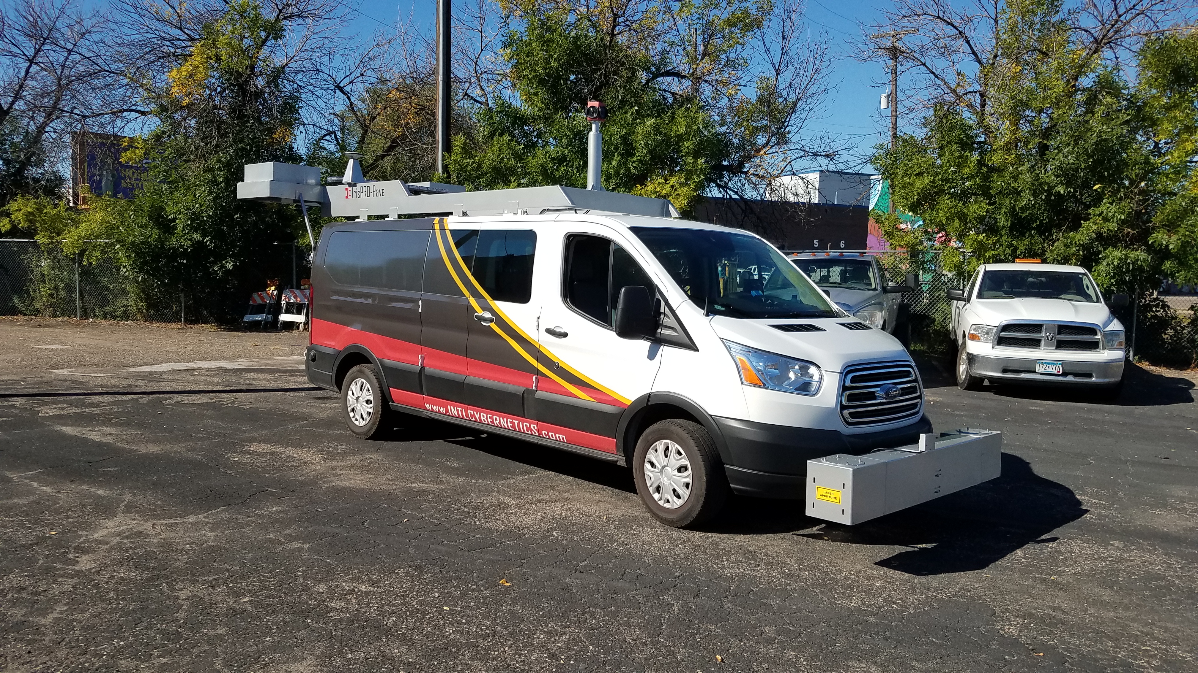 Van with equipment on front and top driving along a city street