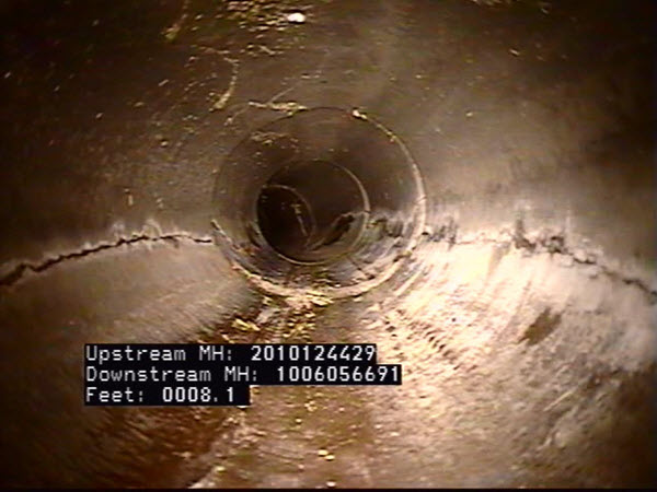 Interior view of storm pipe with cracks along the pipe's length.