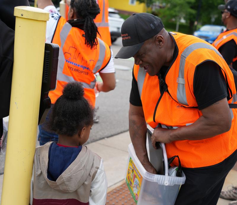 A violence interrupter offers a cookie to a child