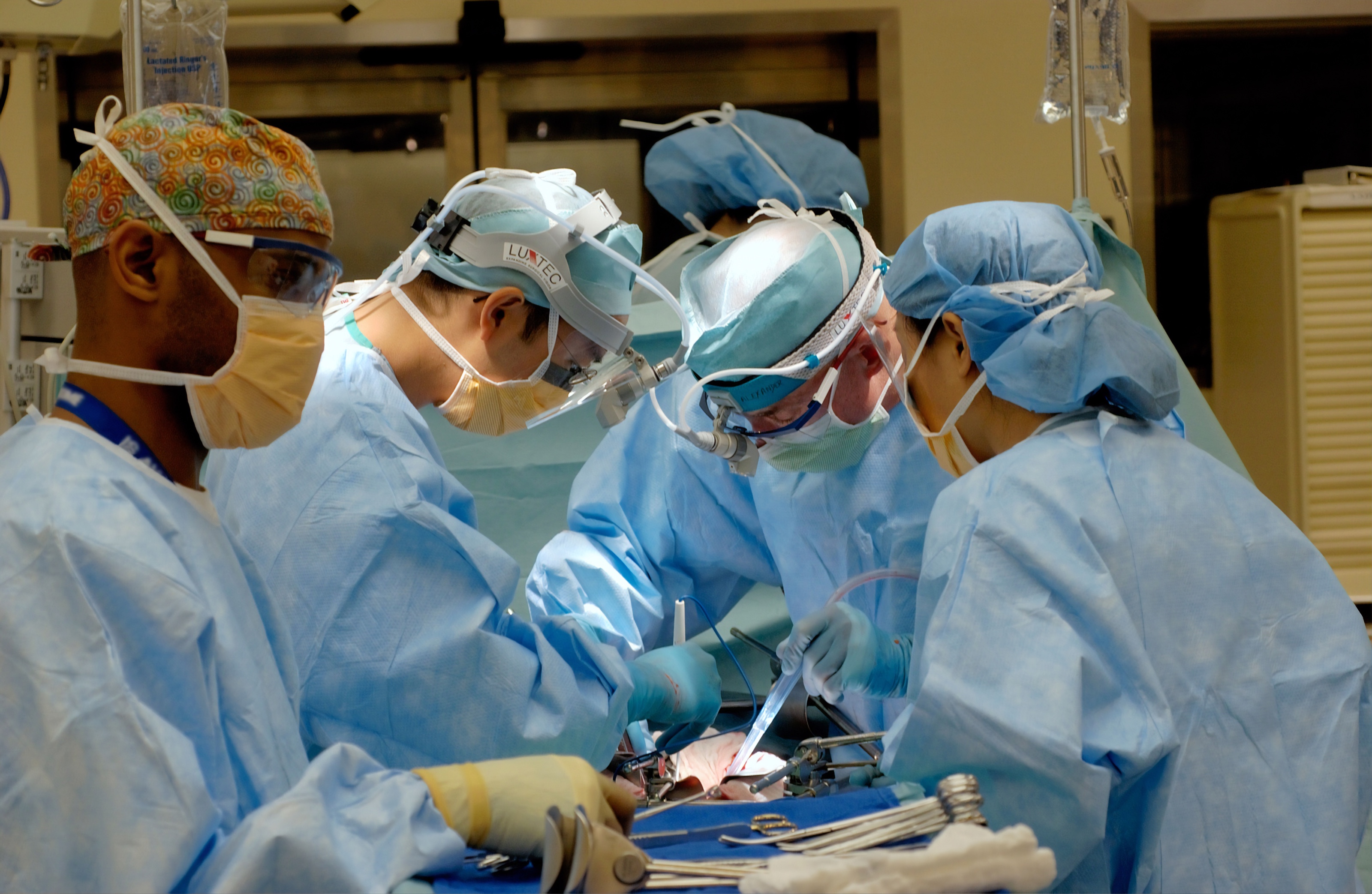 Five surgeons in scrubs working on a patient