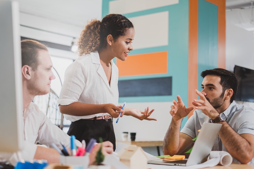 Three people in office setting talking together and smiling