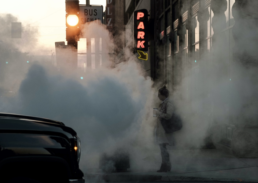 Person on sidewalk with smoke around them