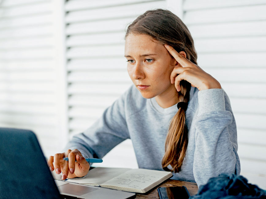 young woman working at a computer with notebook