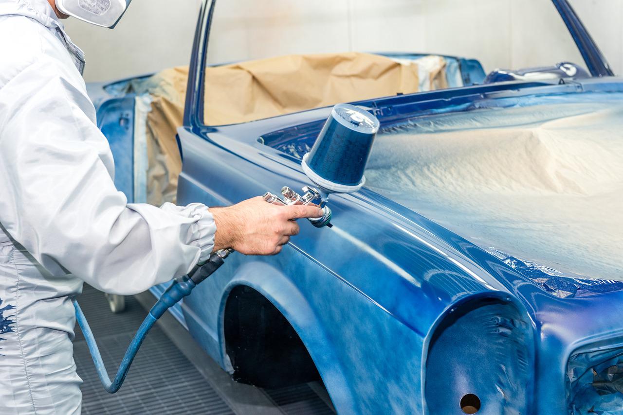 Person's hand painting a car