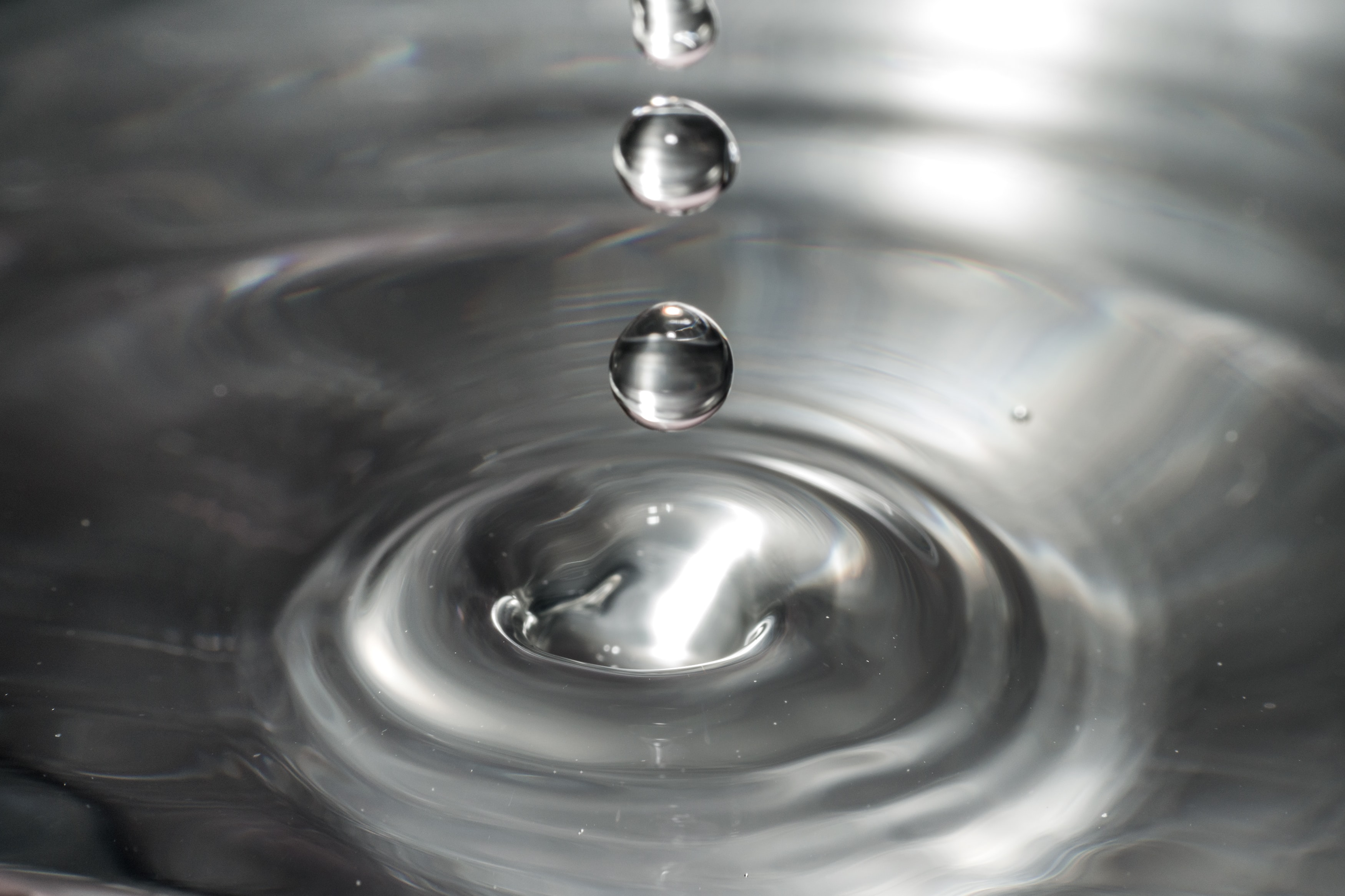 drops of water creating a ripple effect in a larger pool