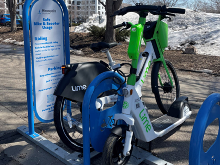 A bike and a scooter locked to a bike parking bay.
