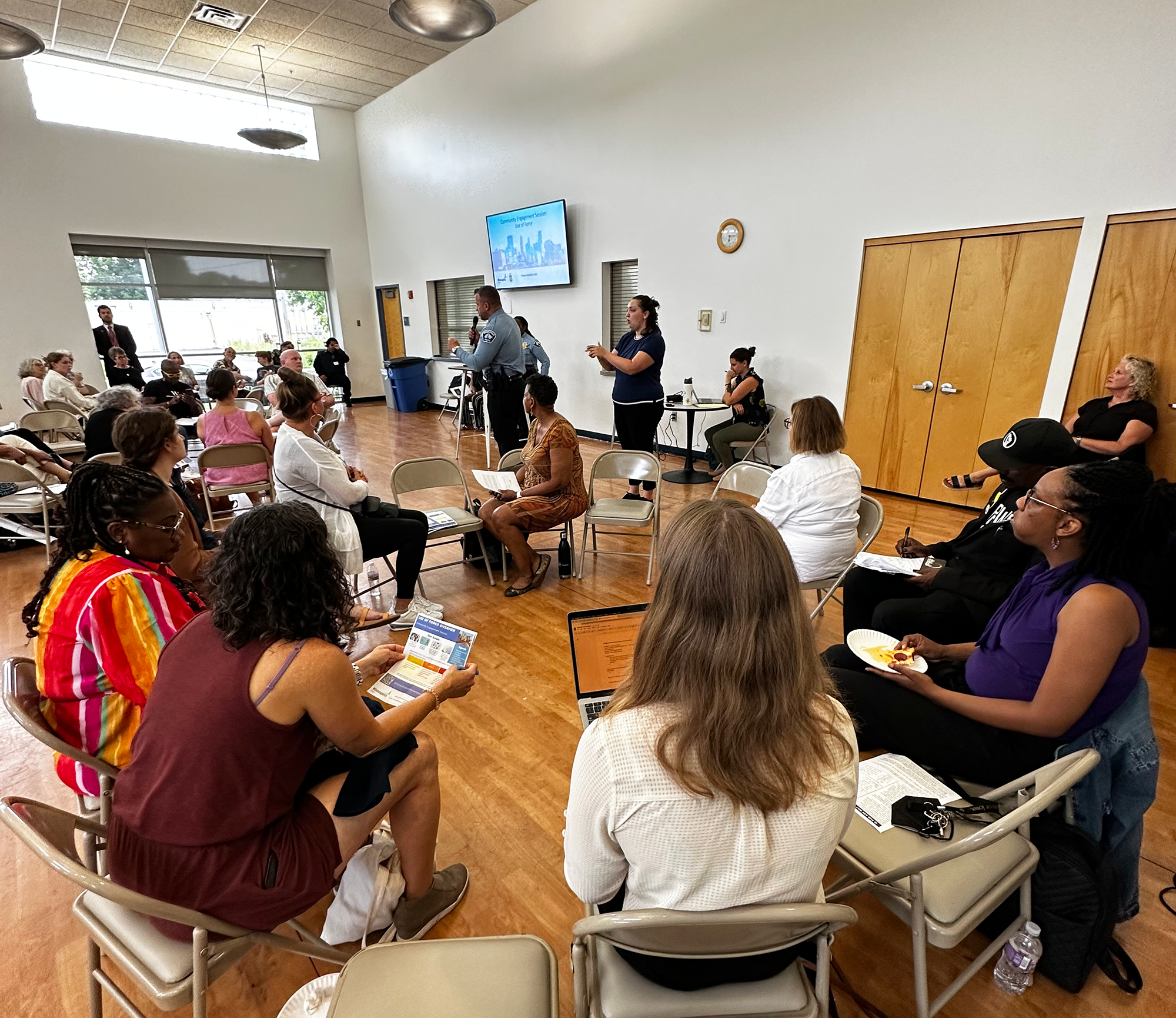 The MPD Implementation Unit hosts a neighborhood convening where community members are seated while listening to MPD Chief O