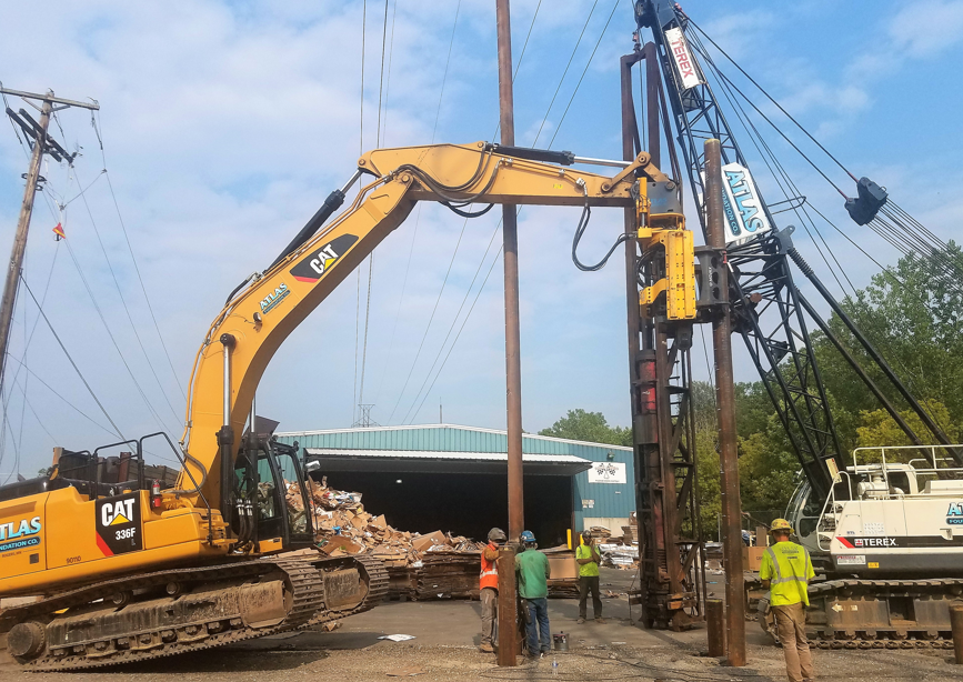 Piles (long support pipes) being driven into the ground with a piece of construction equipment. Piles (long support pipes) being driven into the ground with a piece of construction equipment.