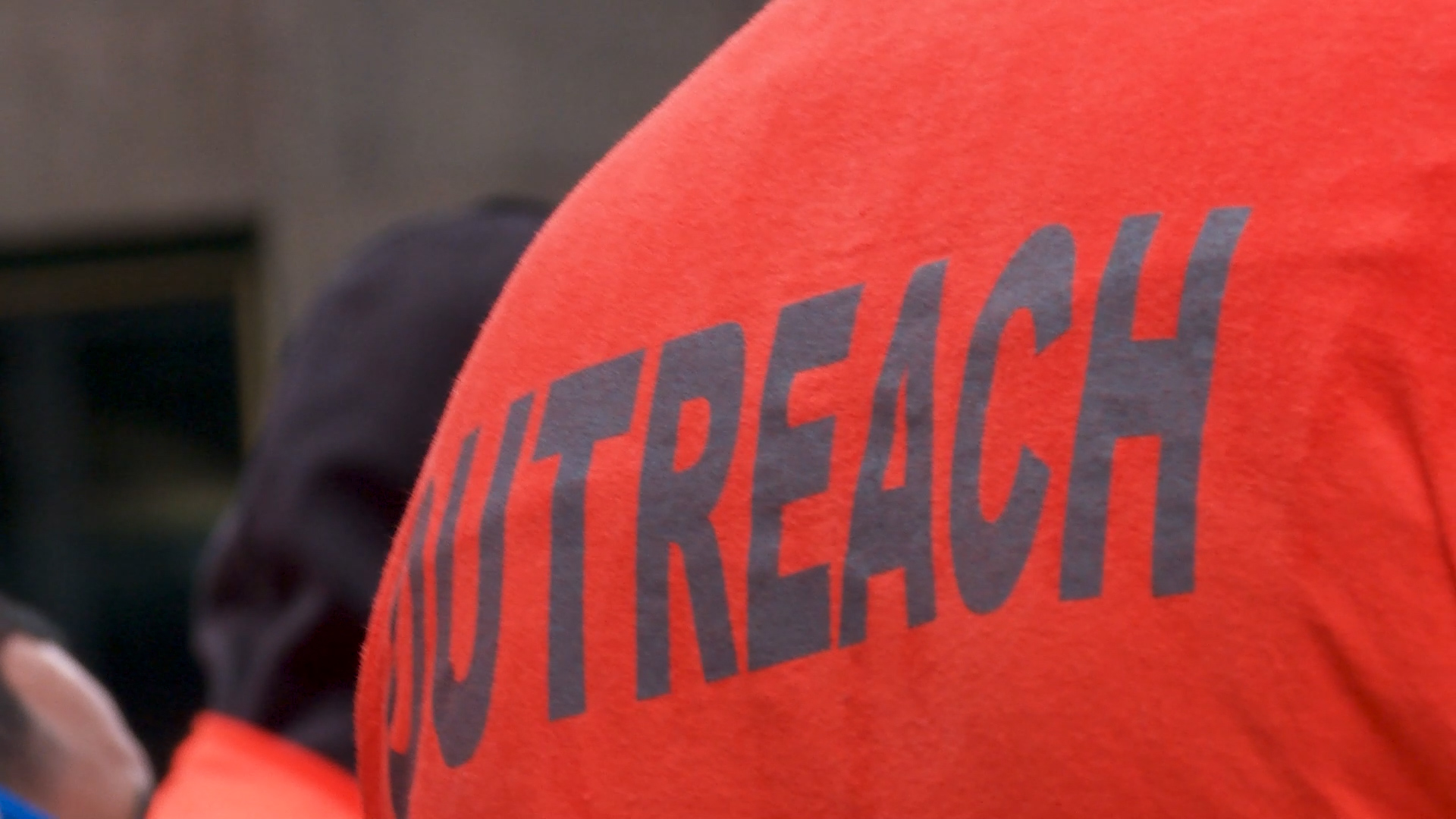 Close up of the word OUTREACH on the back of orange tshirt
