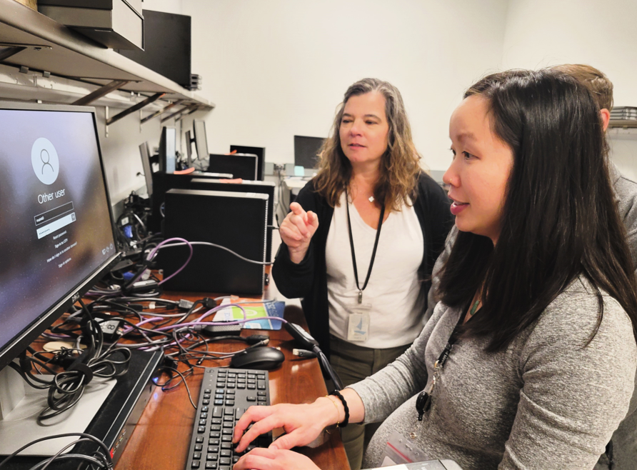 Woman working at a computer getting help