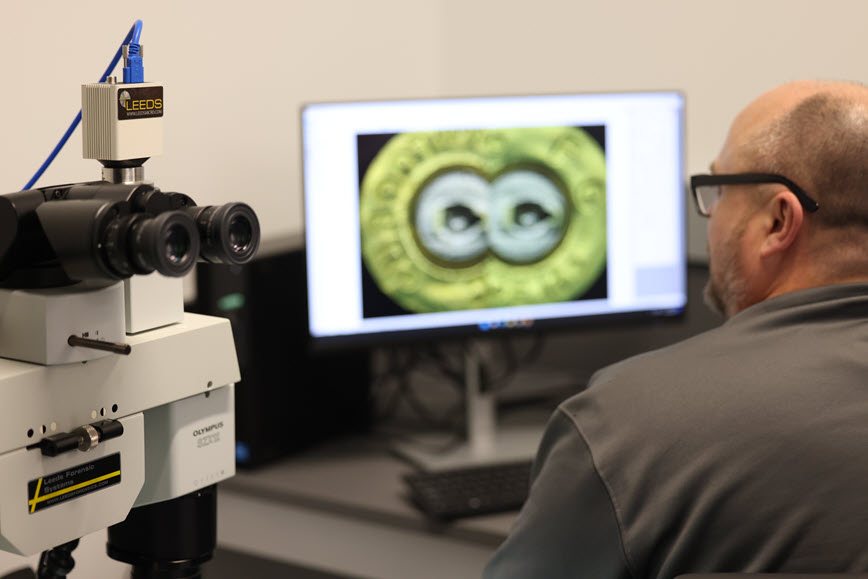 Forensic scientist examining a bullet on a screen Forensic scientist examining a bullet on a screen