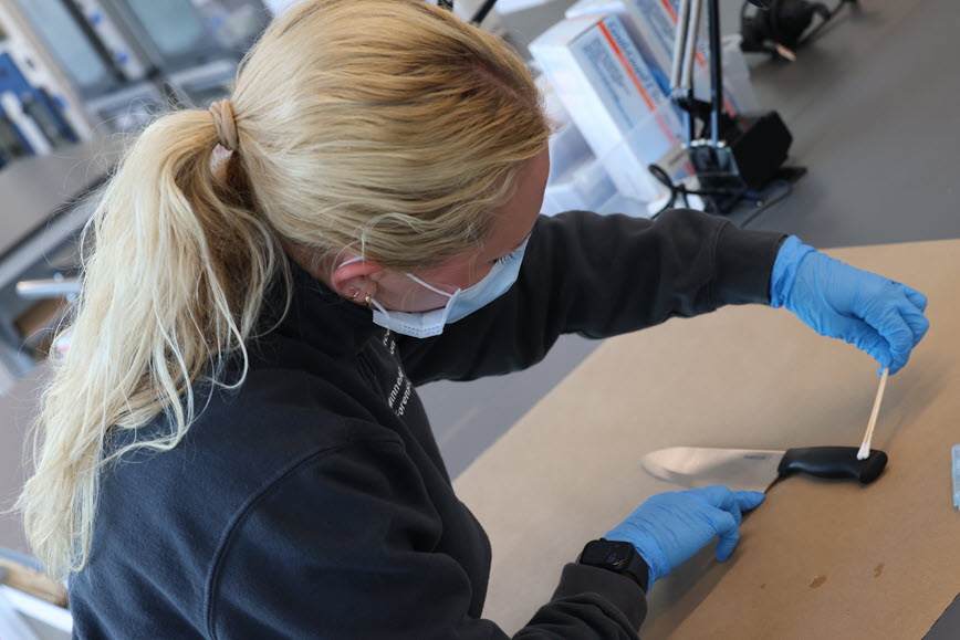 Forensic scientist swabbing a knife Forensic scientist swabbing a knife