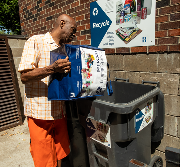 person dumping recycling into a recycling cart an an apartment building