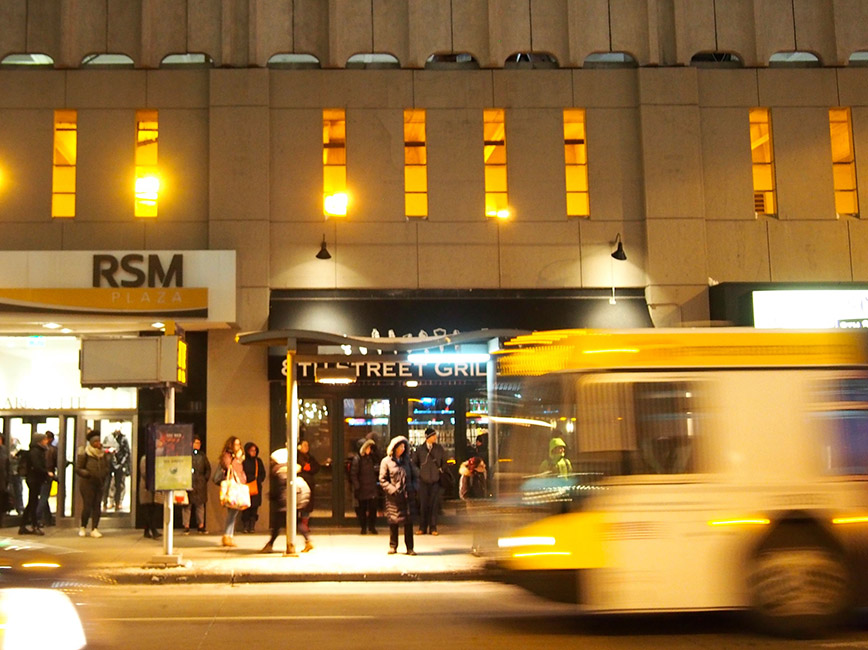 A bus passes in front of storefronts in downtown Minneapolis.