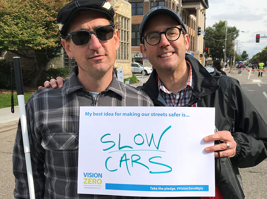 Two people holding a sign that says slow cars
