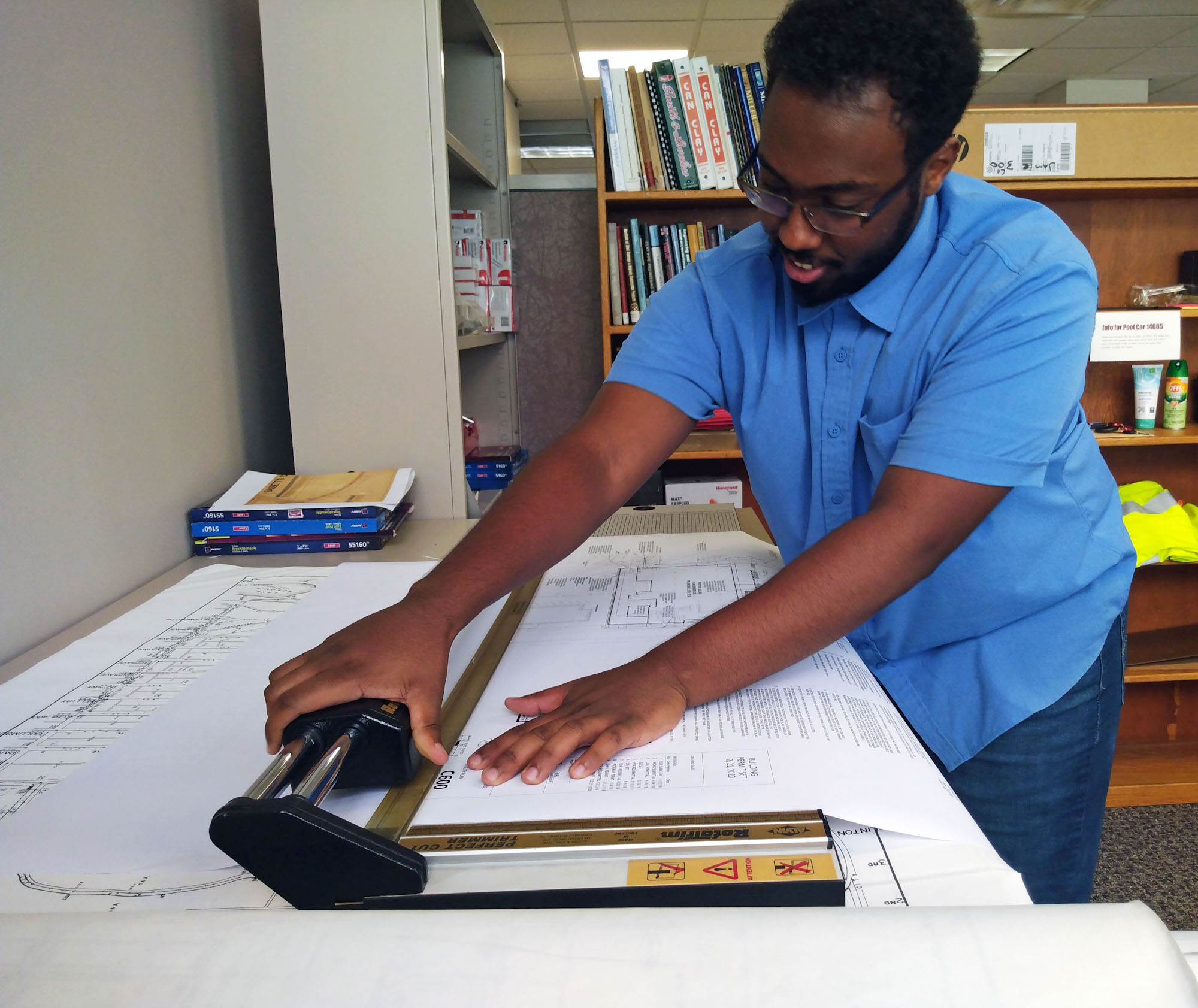 An intern studies building plans in an office. An intern studies building plans in an office.