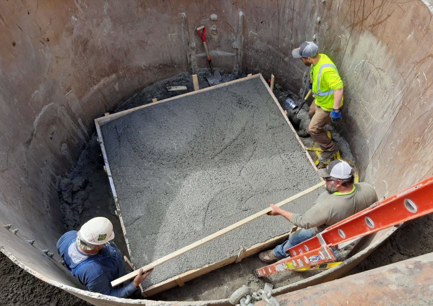 Workers leveling a square of concrete in a manhole Workers leveling a square of concrete in a manhole