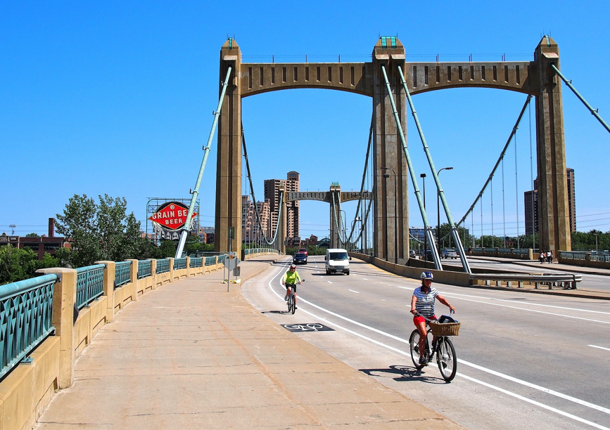 bicyclists on Hennepin Ave bridge with grain belt sign