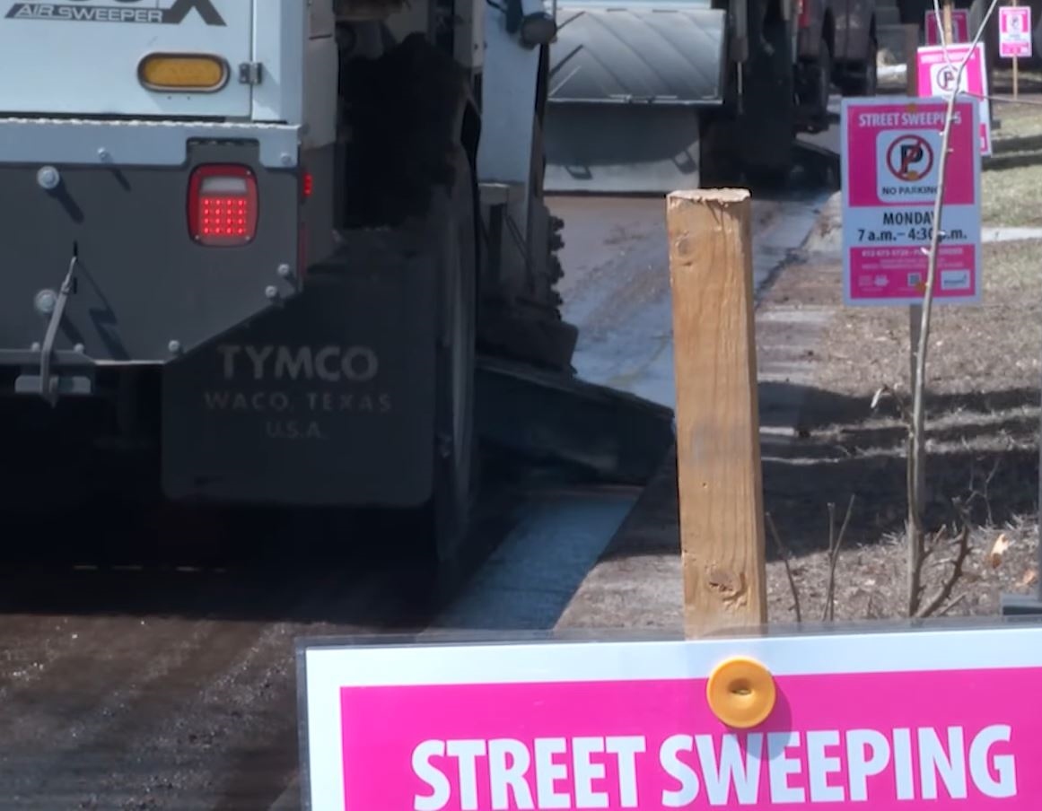 Street sweeper and pink no parking signs