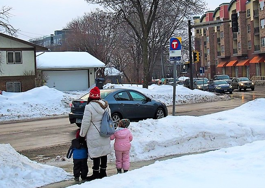 Parent and children near bus stop waiting to board or cross Parent and children near bus stop waiting to board or cross