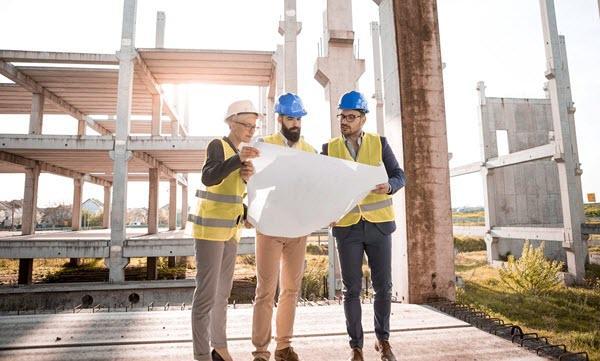 3 people at a construction site reviewing plans
