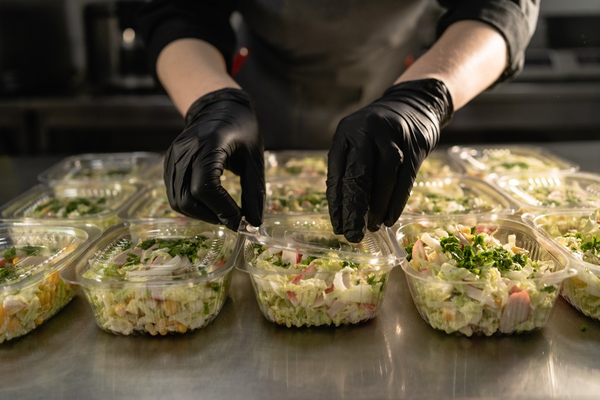 Person's hands putting salad in containers