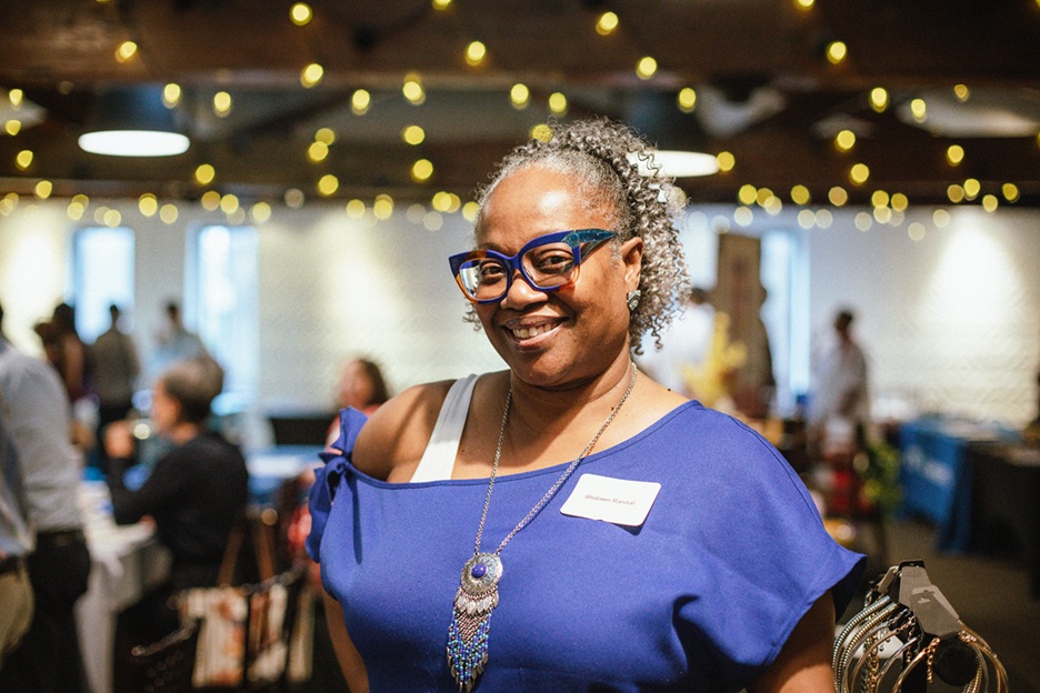 Person in a room with others in the background and lights hung