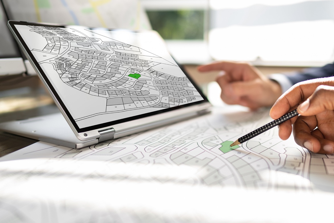 Diverse hands pointing at city zoning map on digital tablet.