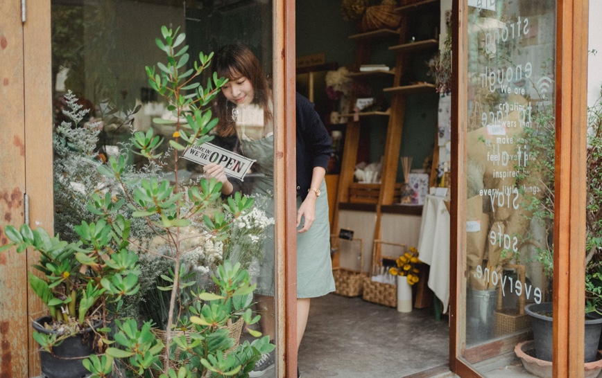 Person putting open sign on door to flower shop