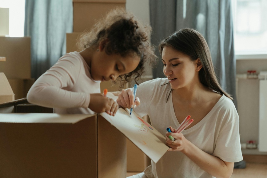Adult and child coloring on a moving box