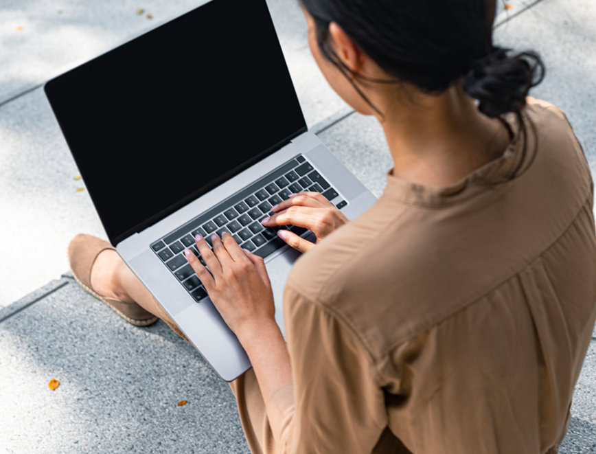 Person typing on laptop outside