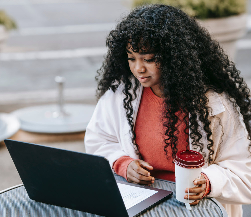 Person using laptop while holding coffee