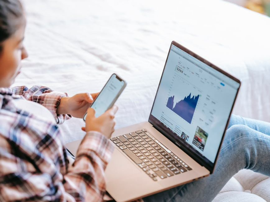 Person looking up data from phone and laptop