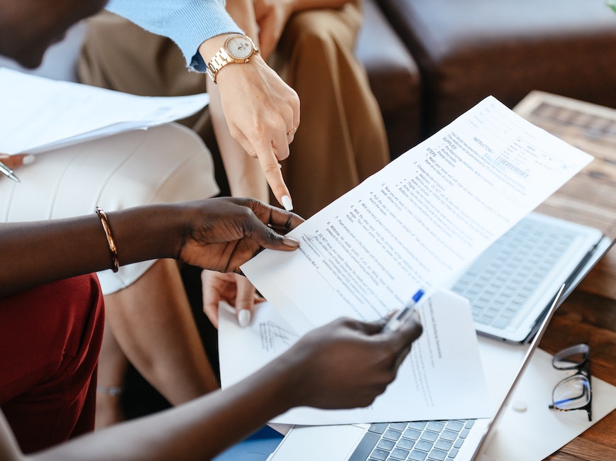 Close up of peoples' hands holding and pointing to paper documents.