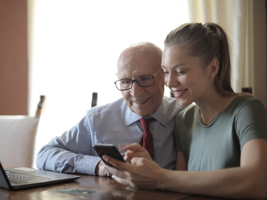 Elderly person and young person using computer and cellphone