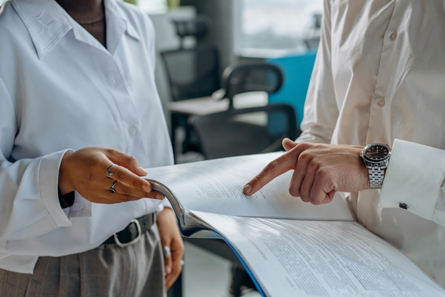Hands of two people holding a document and pointing to content