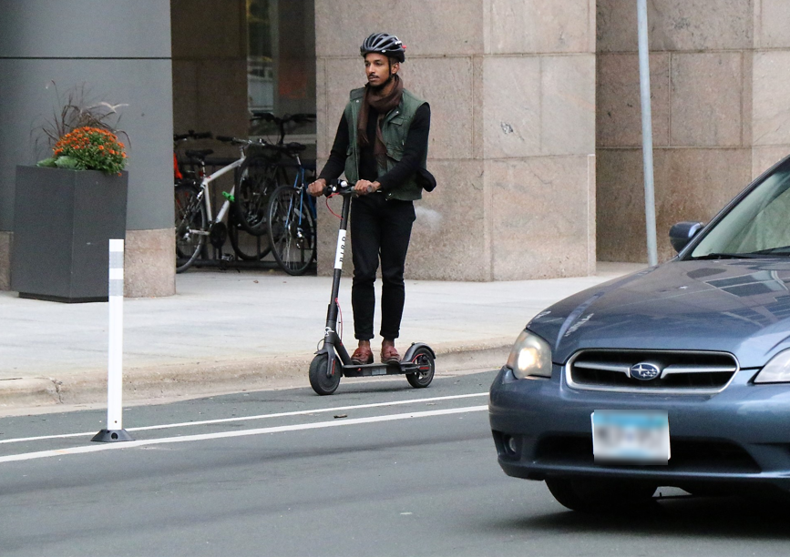 Man riding scooter downtown Minneapolis Man riding scooter downtown Minneapolis