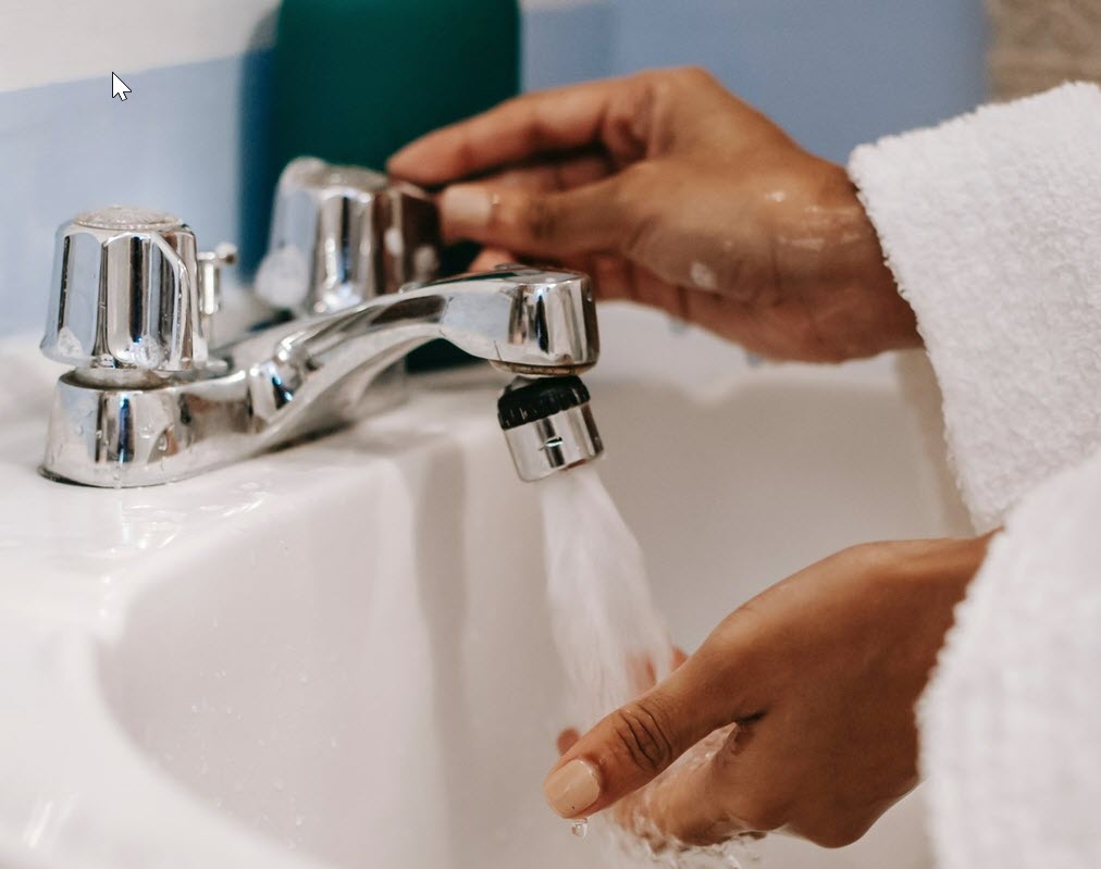 person washing hands in sink