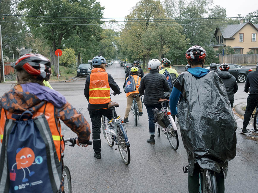 A group of young people on bikes at a stop sign.